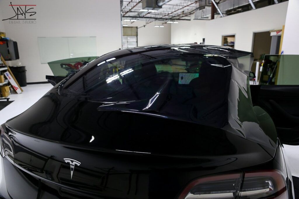 Black Tesla sedan in a garage.