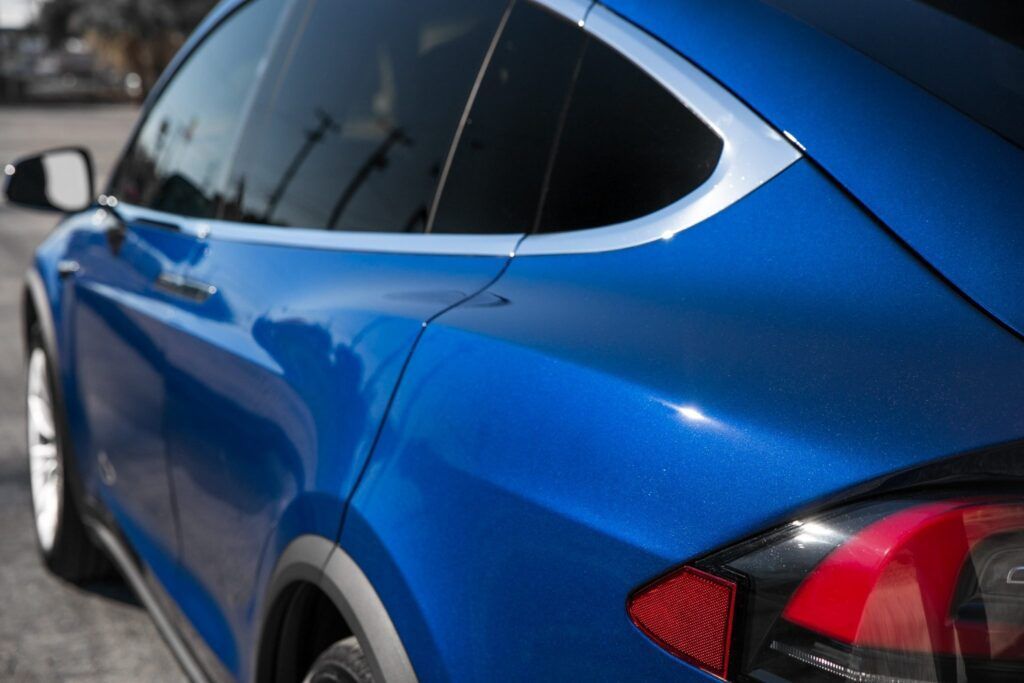 Blue Tesla SUV, close up of the rear, showing tail light and curved window.