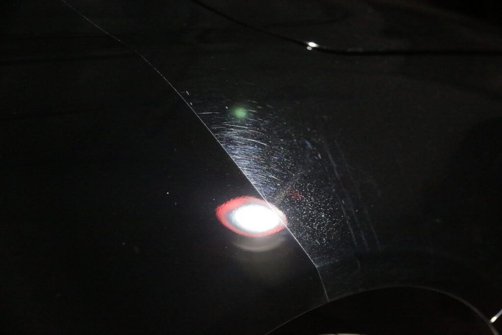 Dark interior car shot, windshield with rain streaks, bright light reflections.
