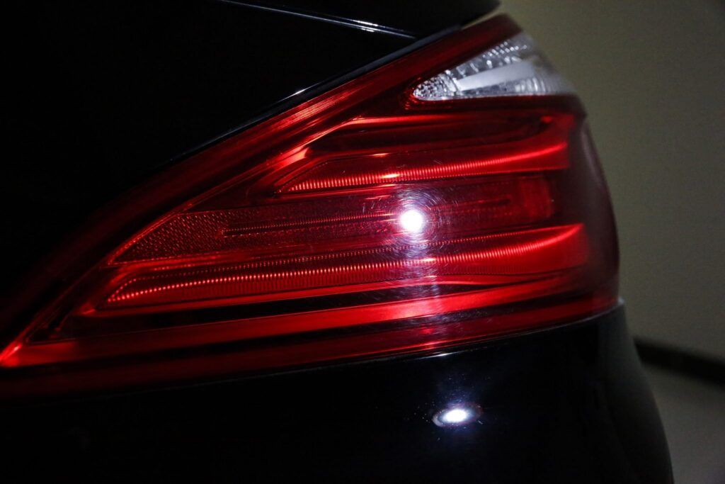 Black car's tail light illuminated red, with white turn signal.