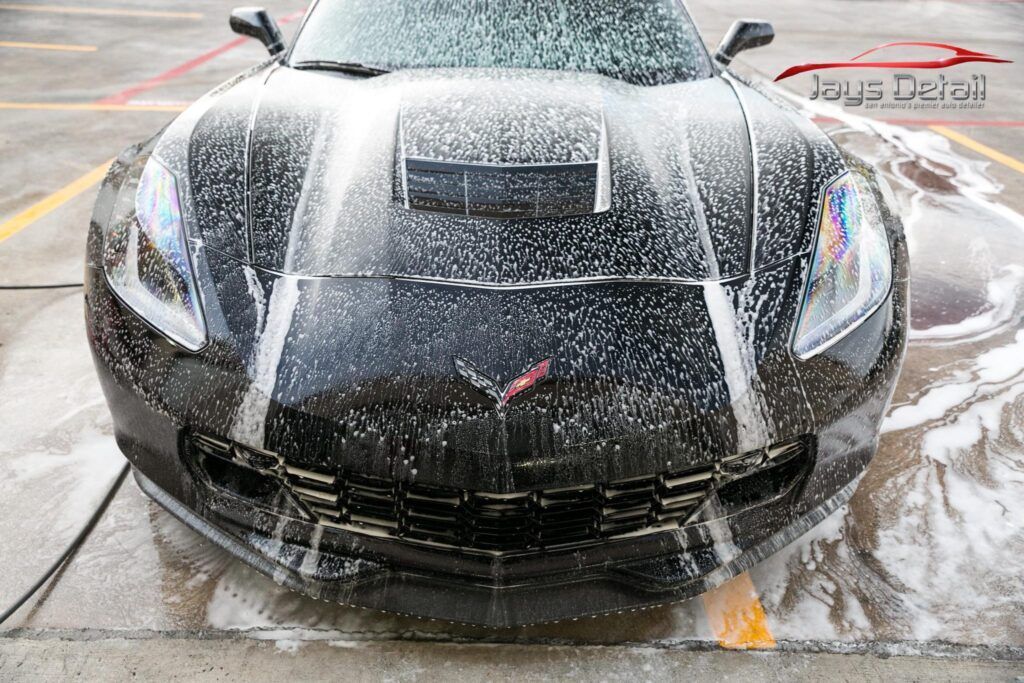 Black Corvette being washed with foamy soap.
