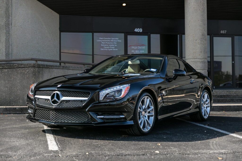 Black Mercedes-Benz convertible parked in front of a building with large windows.