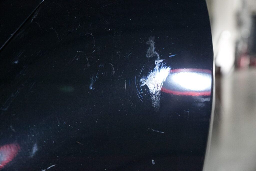 Black car body with white scuff marks and scratches.