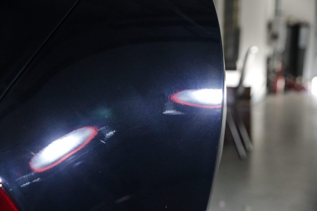 Dark blue car side with swirl marks and reflections.