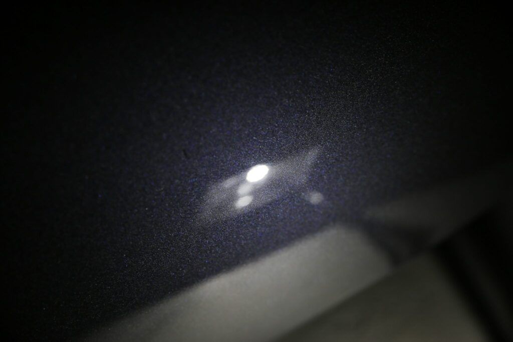 Bright light reflecting off a dark surface, creating a highlighted rectangular shape with smaller spots around it.
