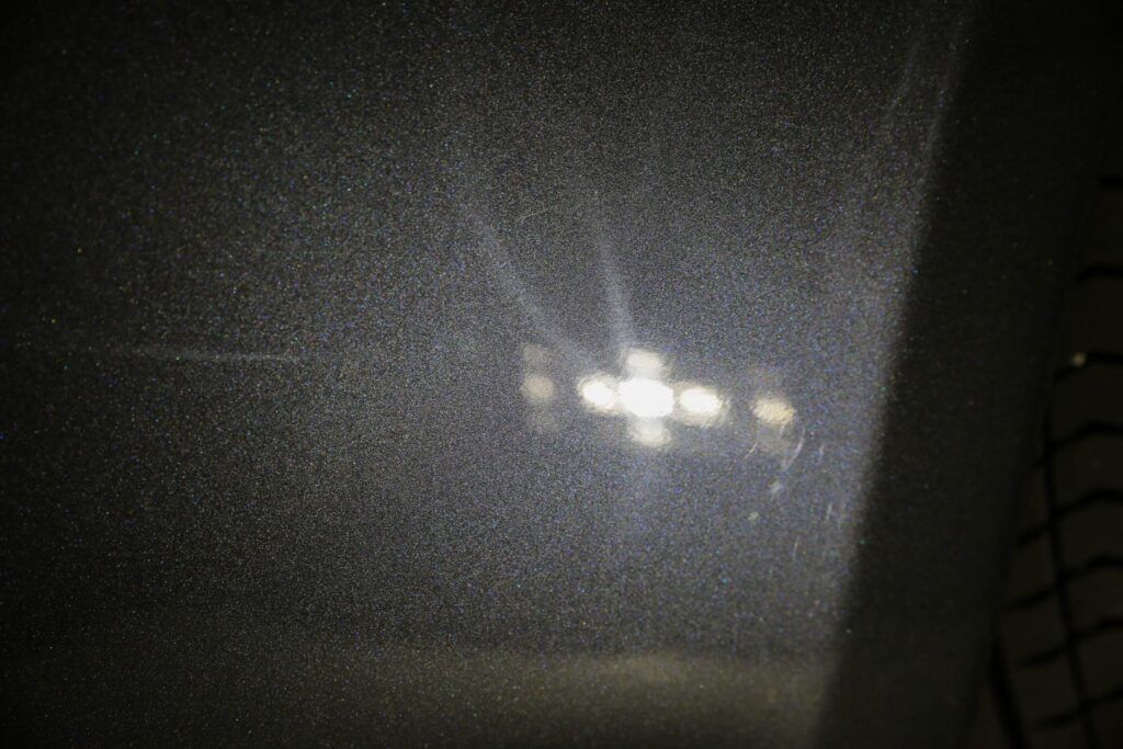 Bright light reflecting on a textured, dark surface; light source out of focus in the center.