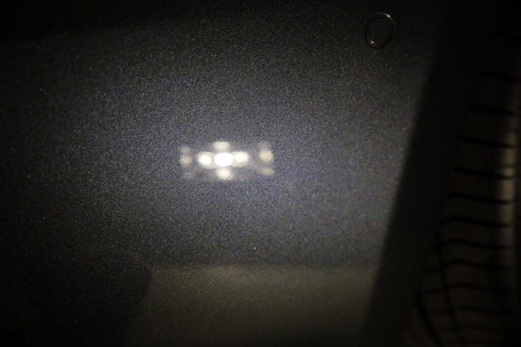 Bright light reflecting on a dark, textured surface, possibly a car interior.