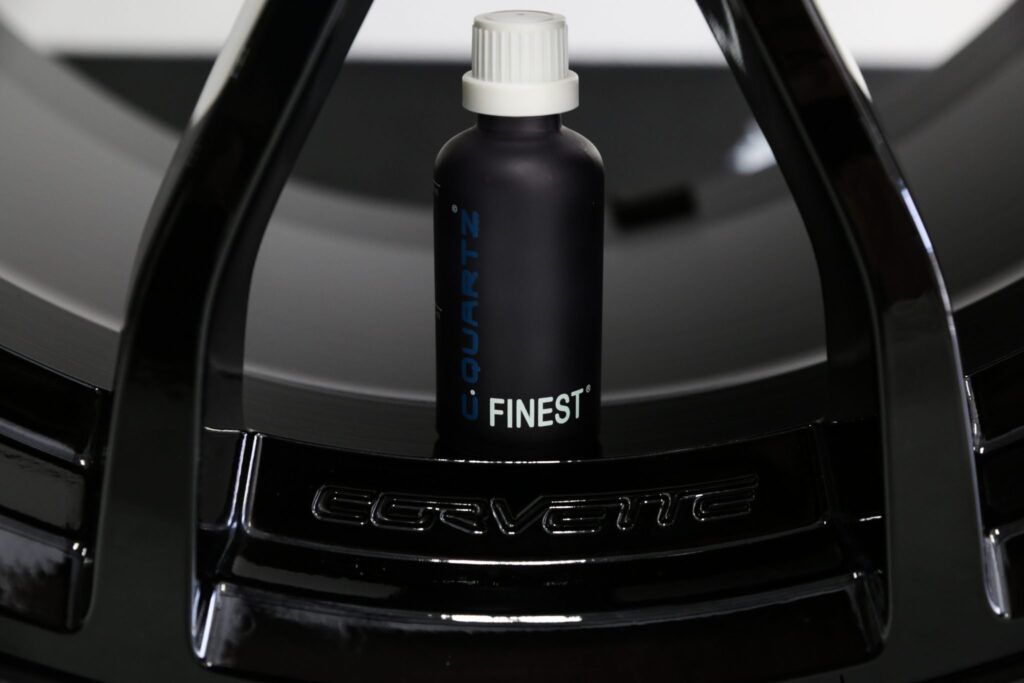 Black ceramic coating bottle on a glossy black Corvette wheel, the word