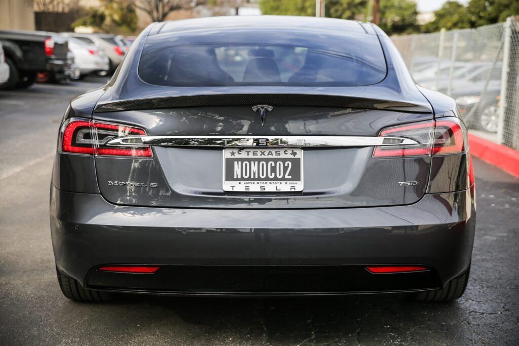 Rear view of a dark gray Tesla sedan with the license plate