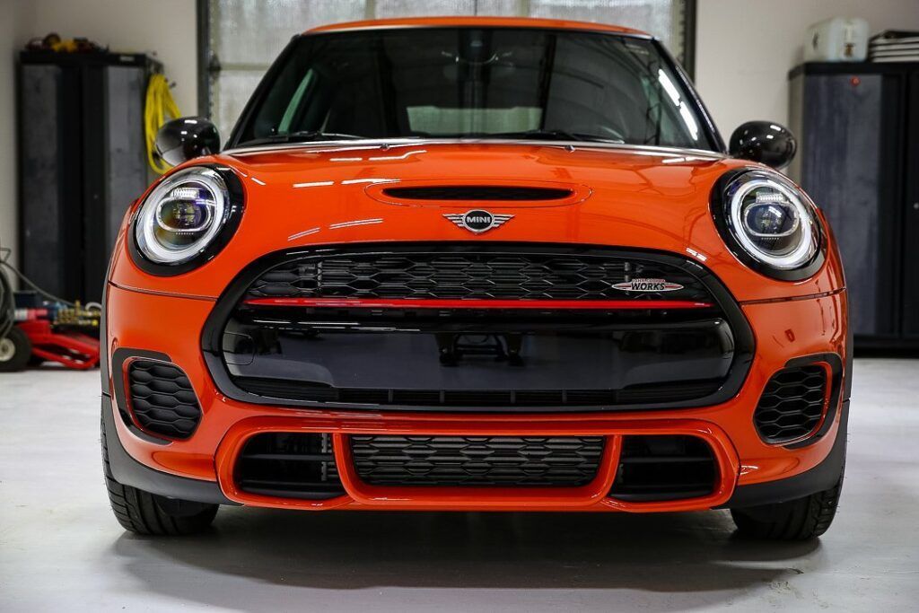 Orange Mini Cooper parked in a garage.