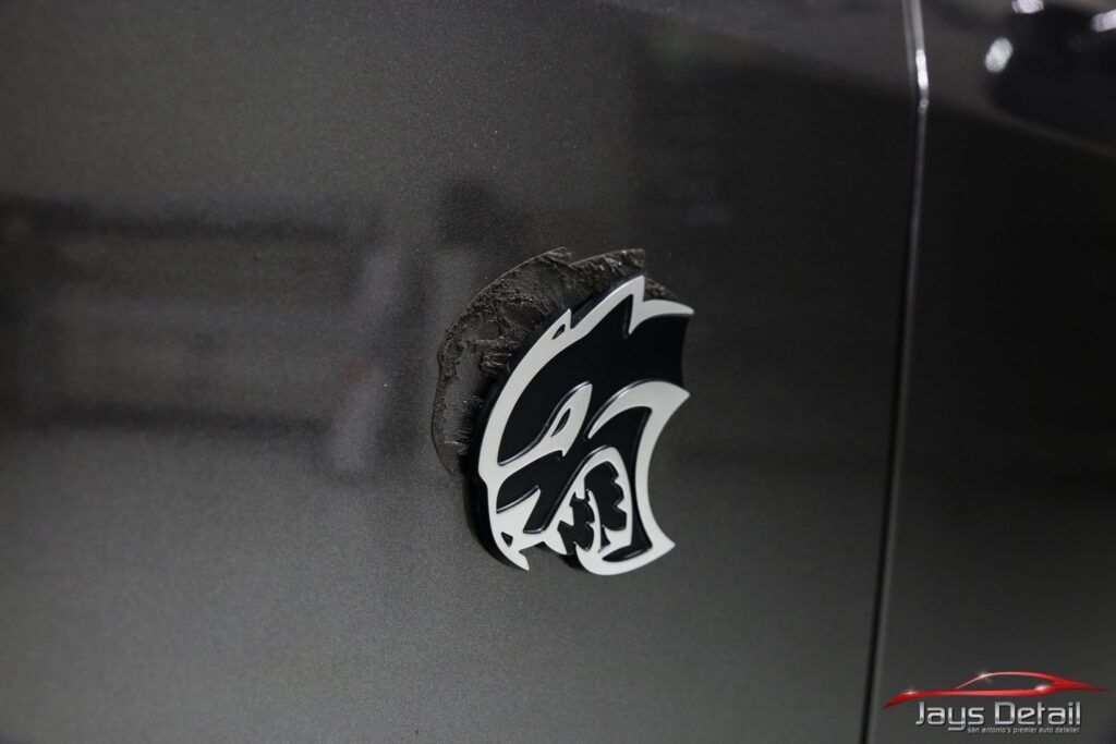 Black car's side panel with shimmering paint, reflecting light in a garage.