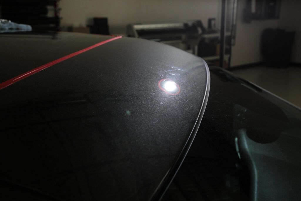Black car roof with swirls and light reflections.