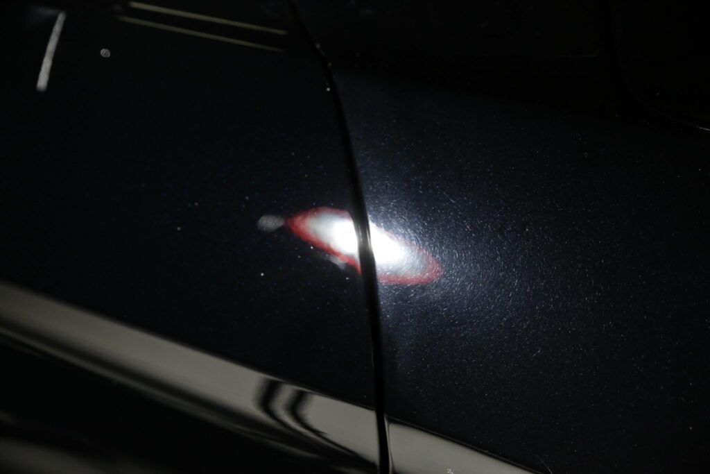 Black car door with light reflecting small spots.