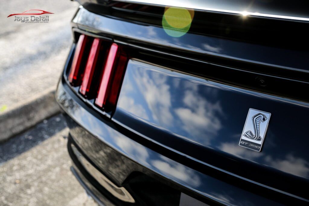 Close-up of a black Ford Mustang Shelby tail end with iconic vertical red tail lights and emblem.