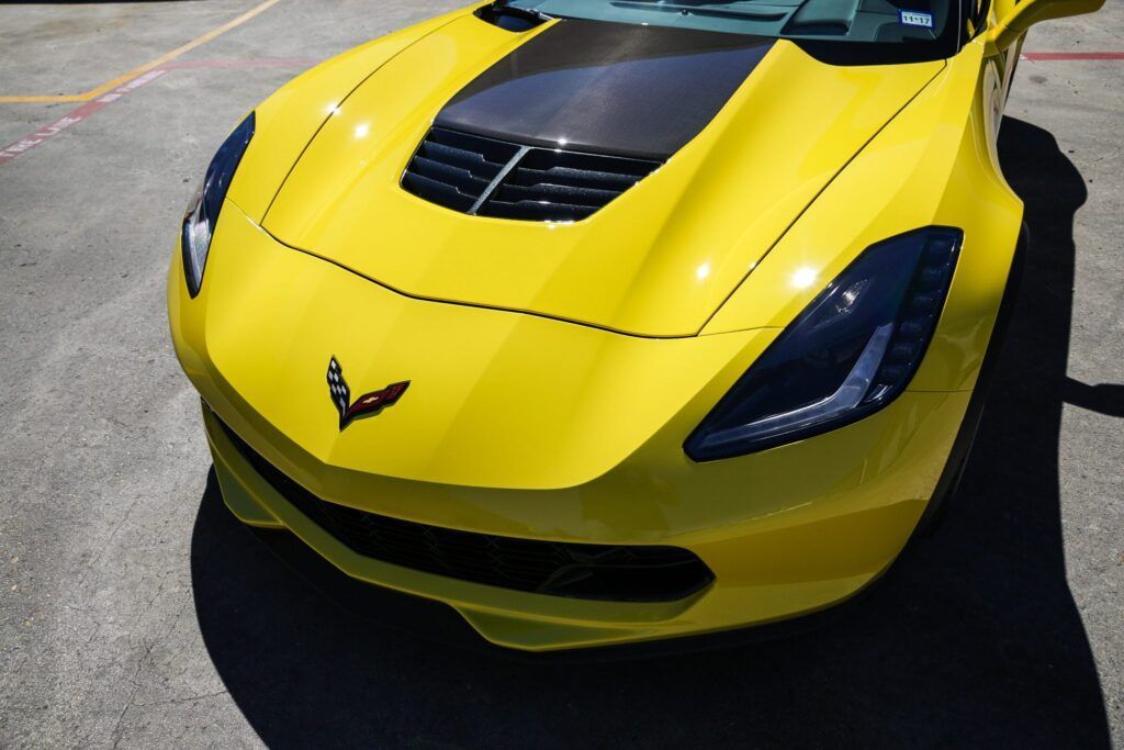 Yellow Corvette with black hood accent on a sunny day.