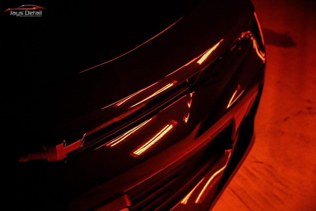 Black car hood reflecting orange light.