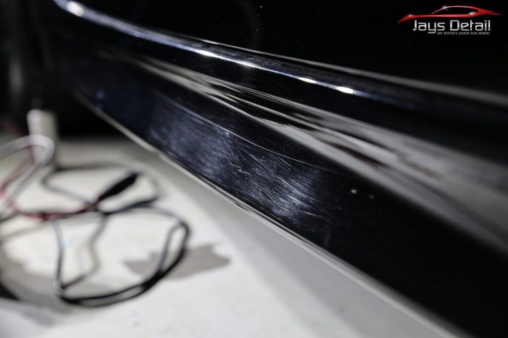 Black car door sill, close-up, showing imperfections and detailing work.