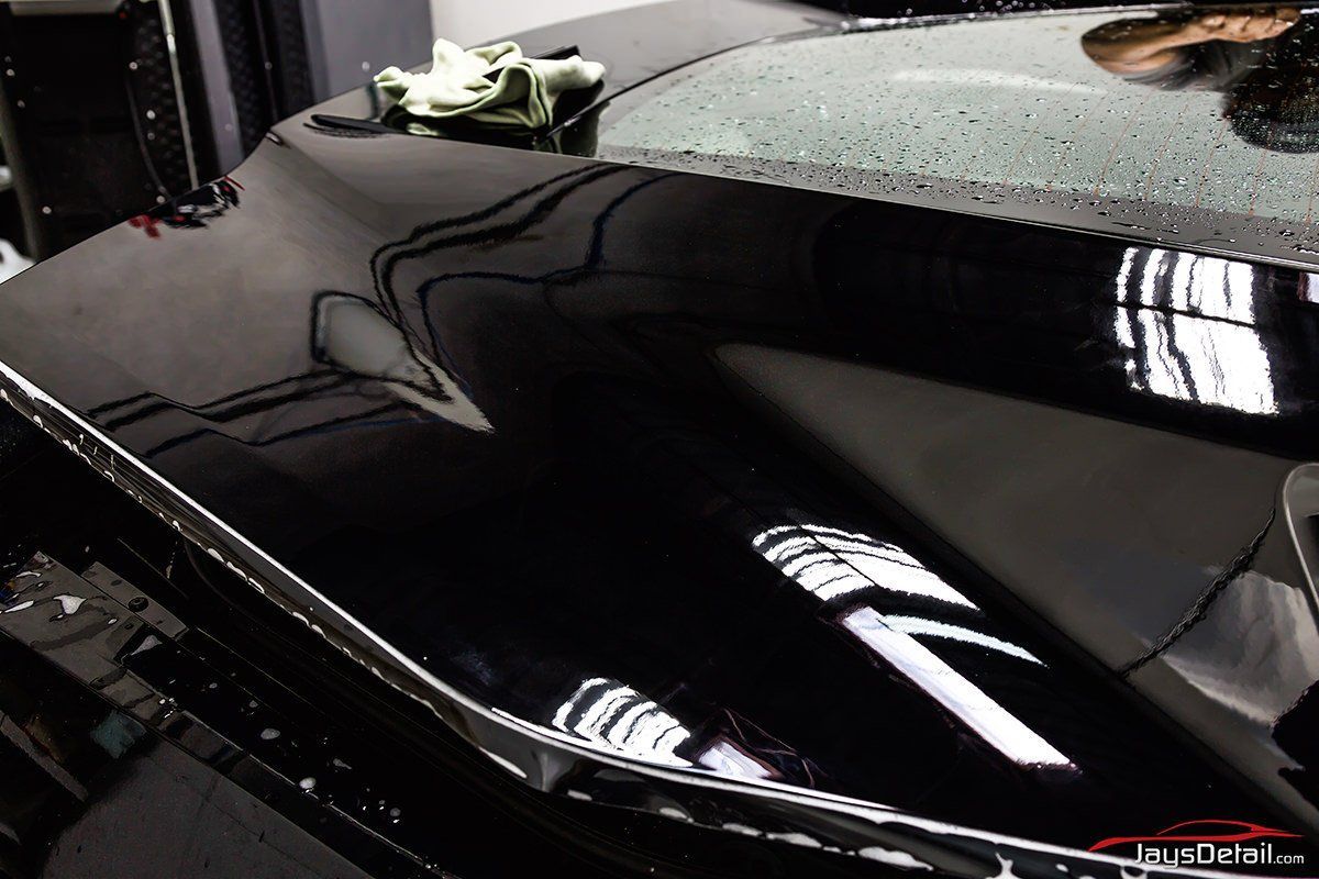 Black car hood reflecting light, with a microfiber cloth on top.