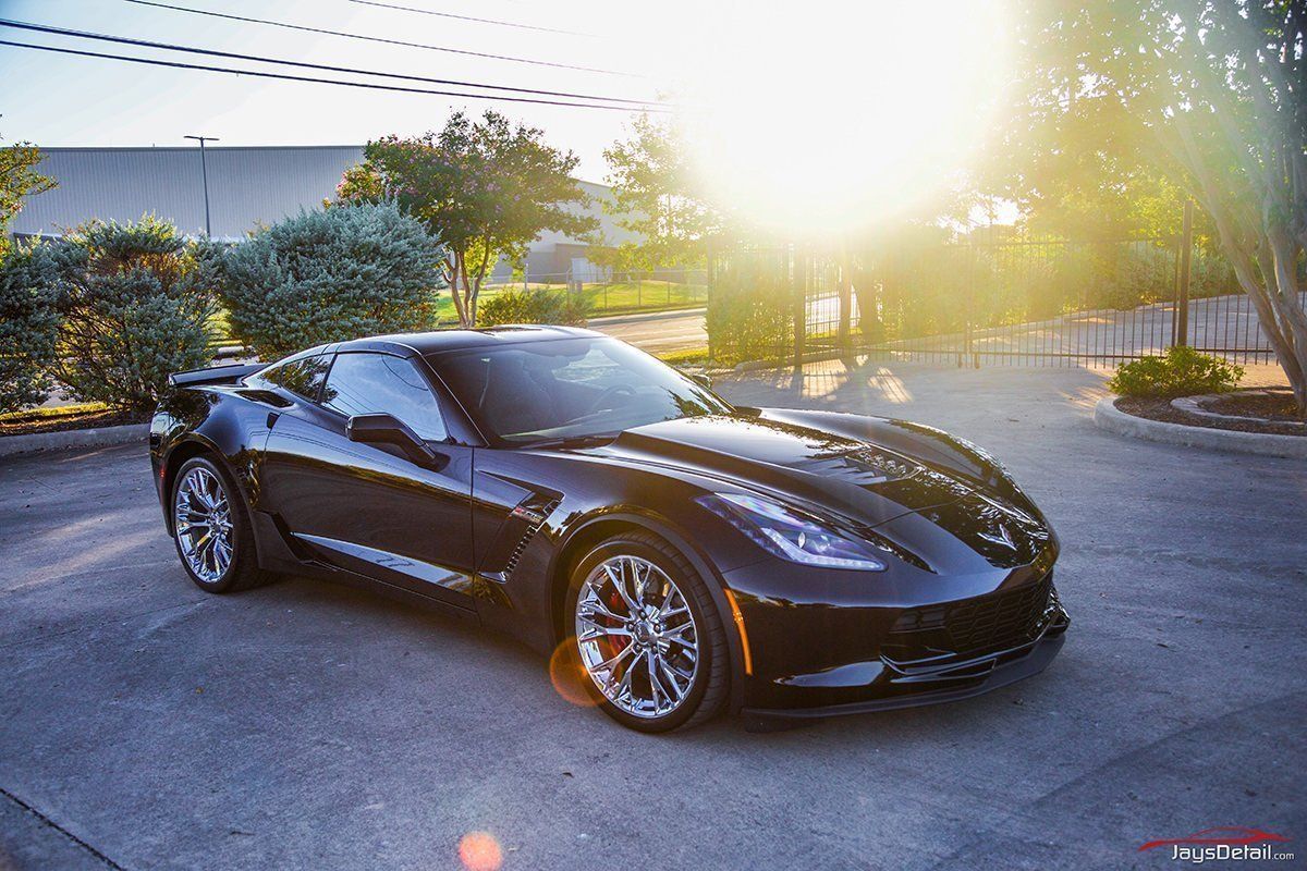 Black Corvette parked outside with the sun shining brightly.