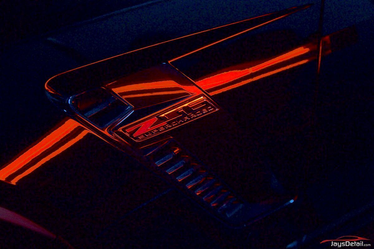 Close-up of a black car hood with red stripes and a