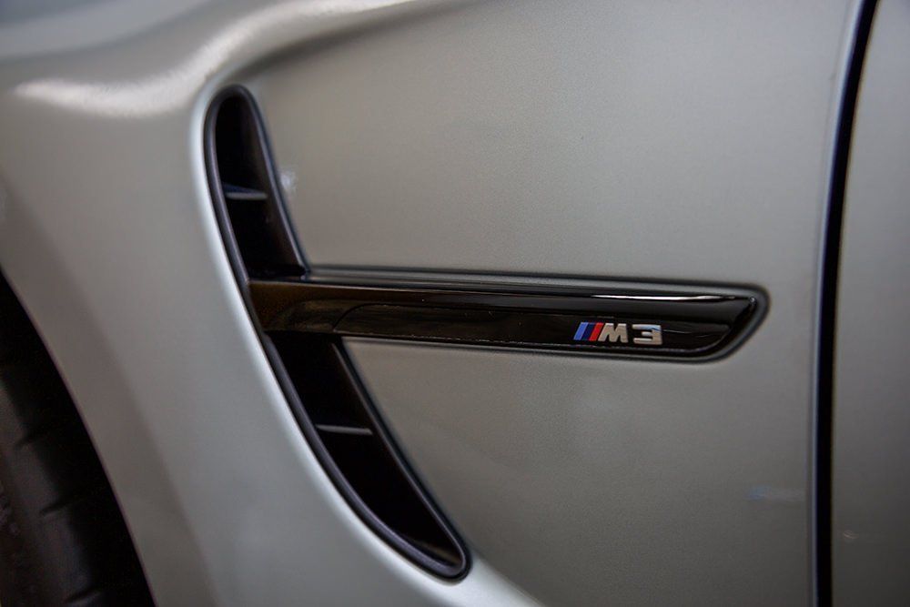 Silver BMW M3 side vent with black trim and M3 badge.