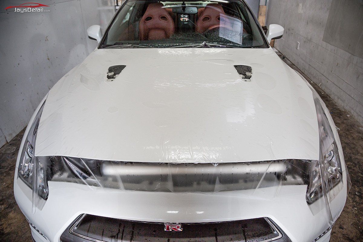 White car in a car wash. Two smiling faces visible through the windshield.