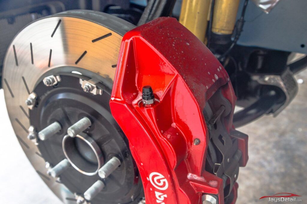 Red Brembo brake caliper on a slotted rotor.