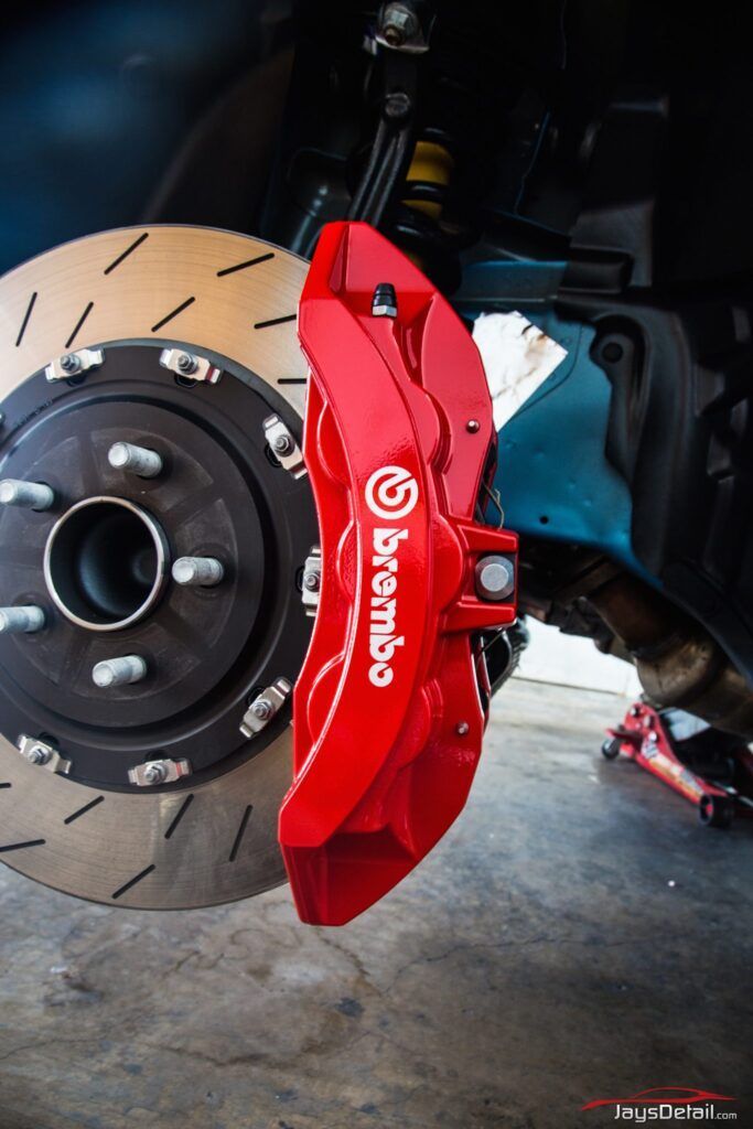 Red Brembo brake caliper on a slotted rotor. Car part, close-up.