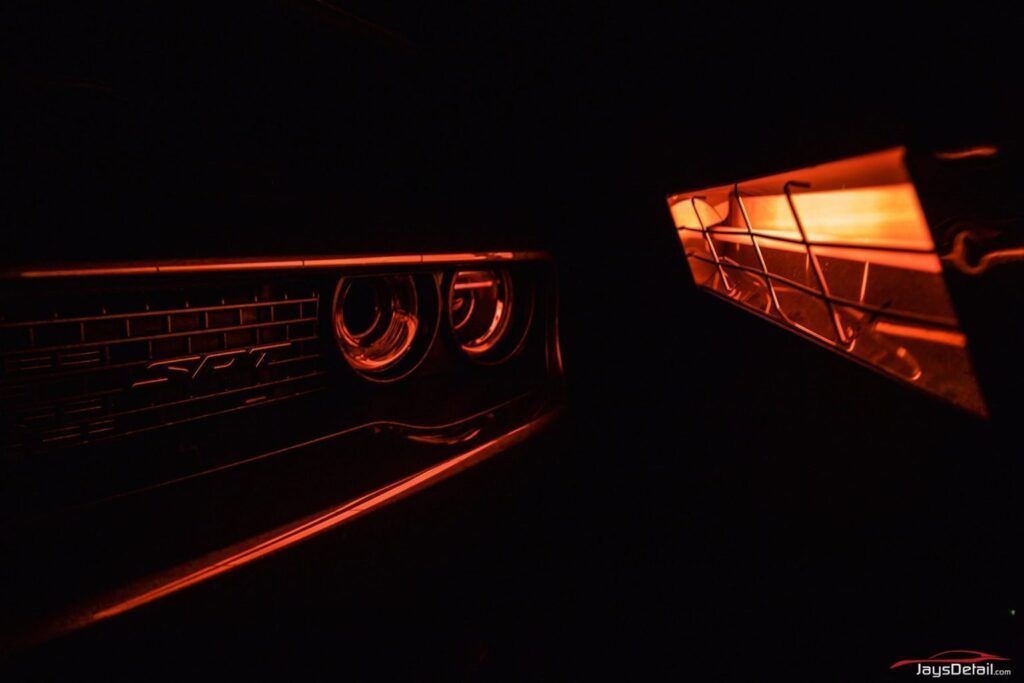 Orange lit-up car headlights and grille in the darkness.