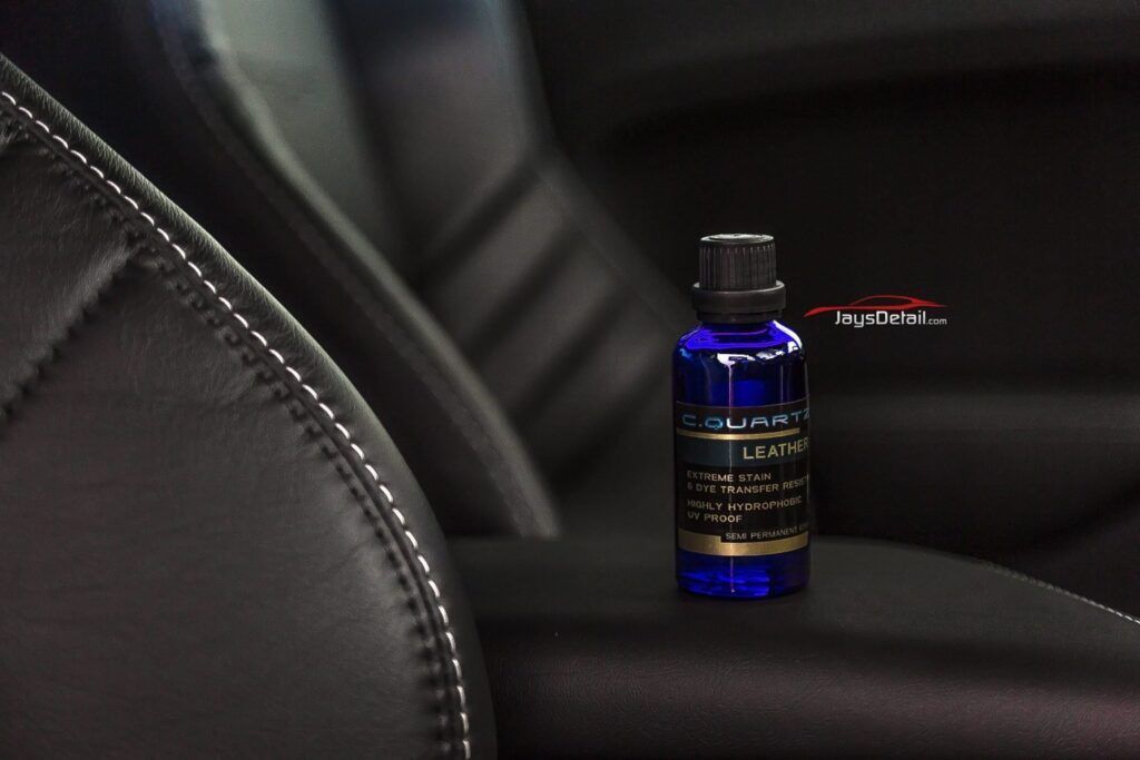 Blue bottle of car leather cleaner on black car seat.