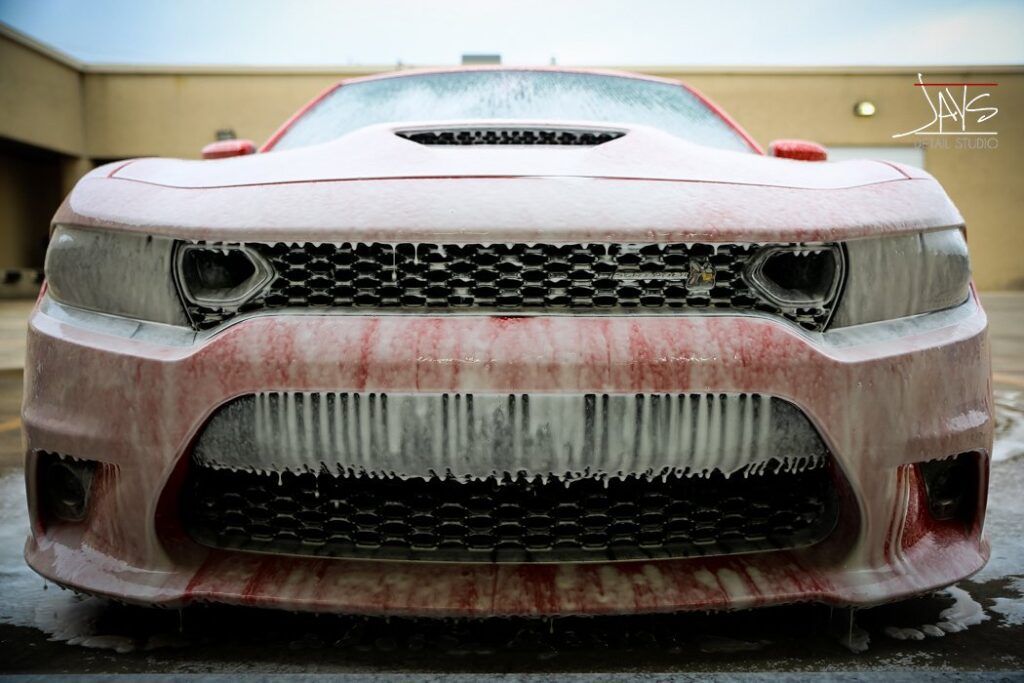Red Dodge Charger covered in icicles, parked outside.