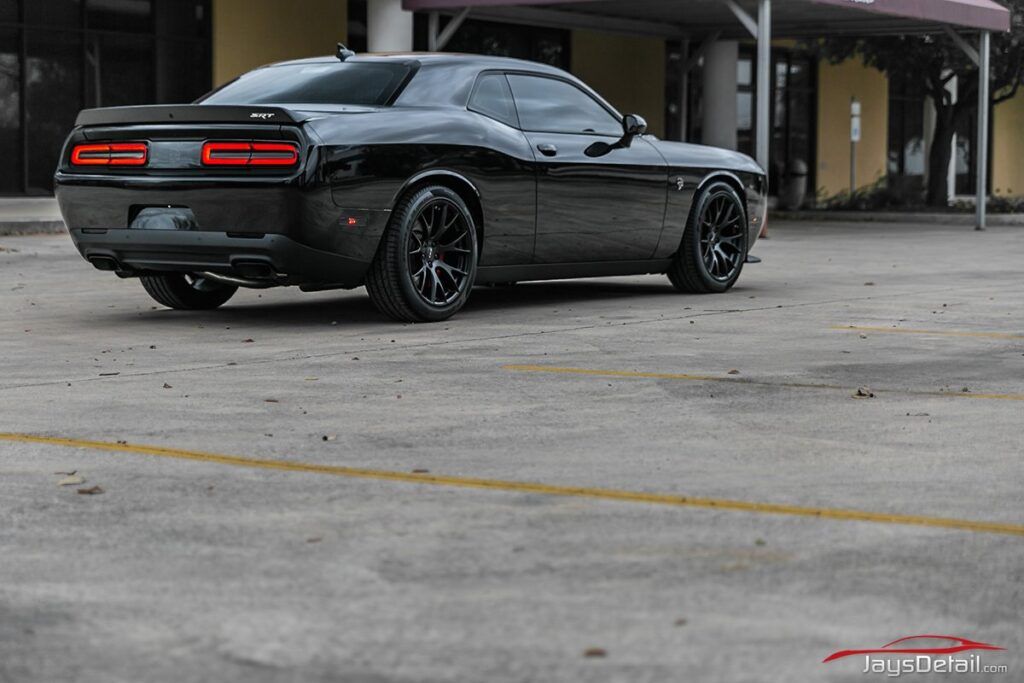 Black Dodge Challenger parked in a lot.
