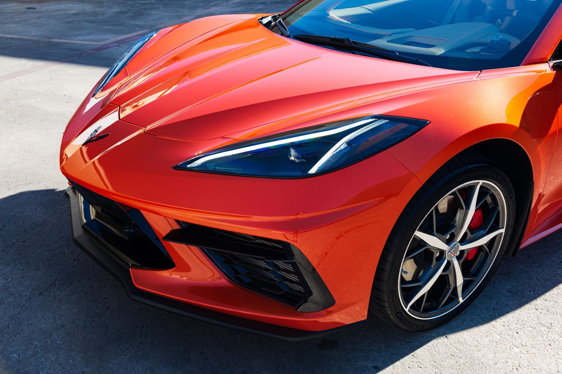 Orange sports car's front with black accents, black wheels, and red brake calipers.