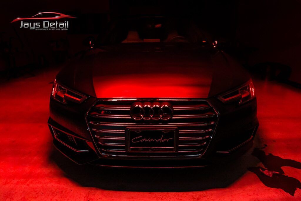 Black Audi car, illuminated with red light, front view.