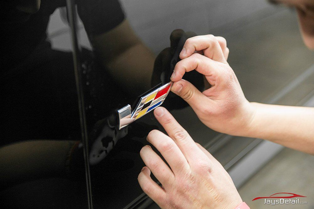 Person attaching a colorful emblem to a black car door.