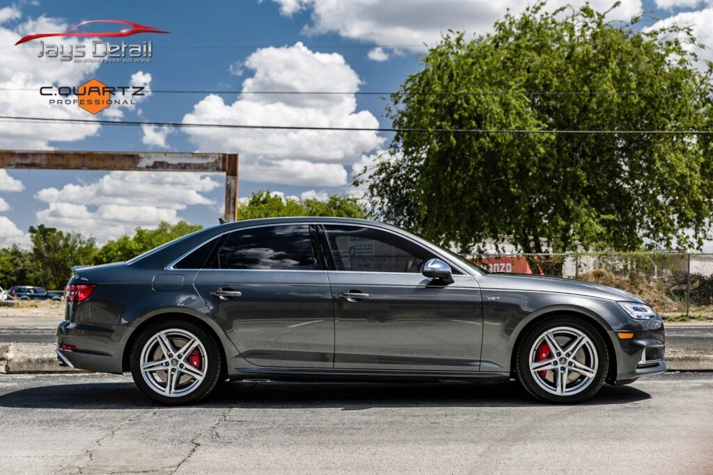 Gray Audi sedan with red brake calipers, parked on a city street.