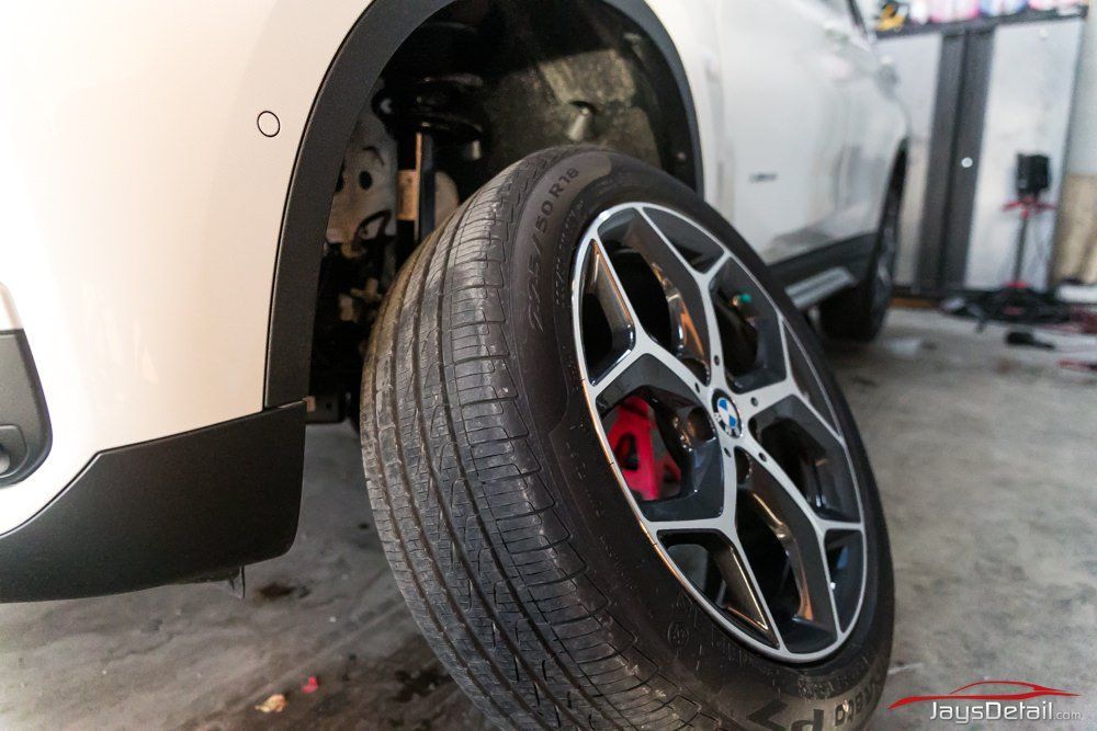 White car with a removed tire, showing a red brake caliper.