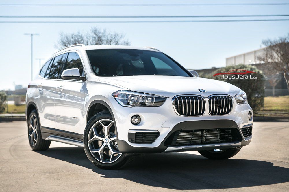 White BMW X1 SUV parked on a sunny day; features black grill, alloy wheels.