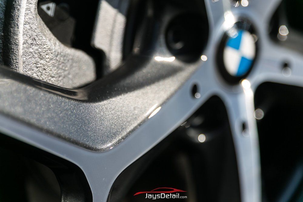 Close-up of a BMW wheel rim, showcasing a gray and silver finish with the BMW logo at the center.