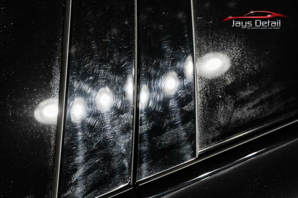 Black car panel with scratches and reflections.