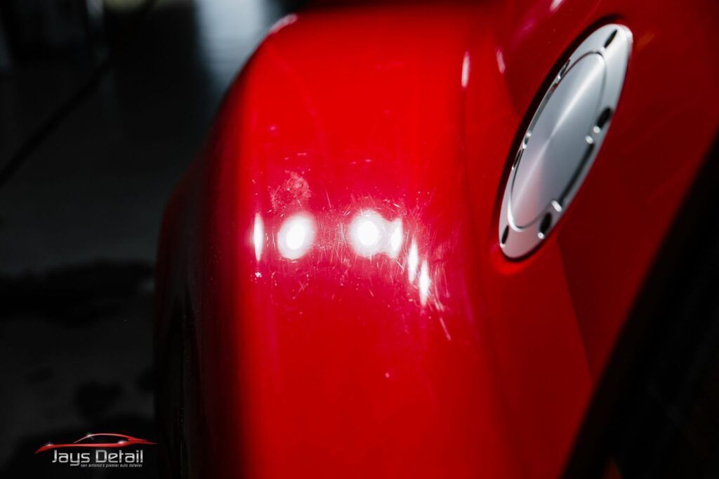 Red car fender with visible scratches and gas cap.