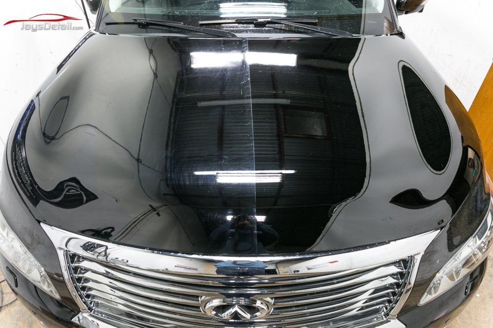Black car hood, half polished, showing shine comparison. Front view.