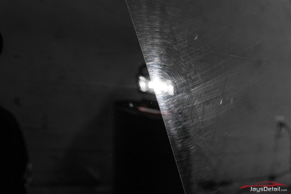 Black car paint, half polished, showing before and after with swirl marks.