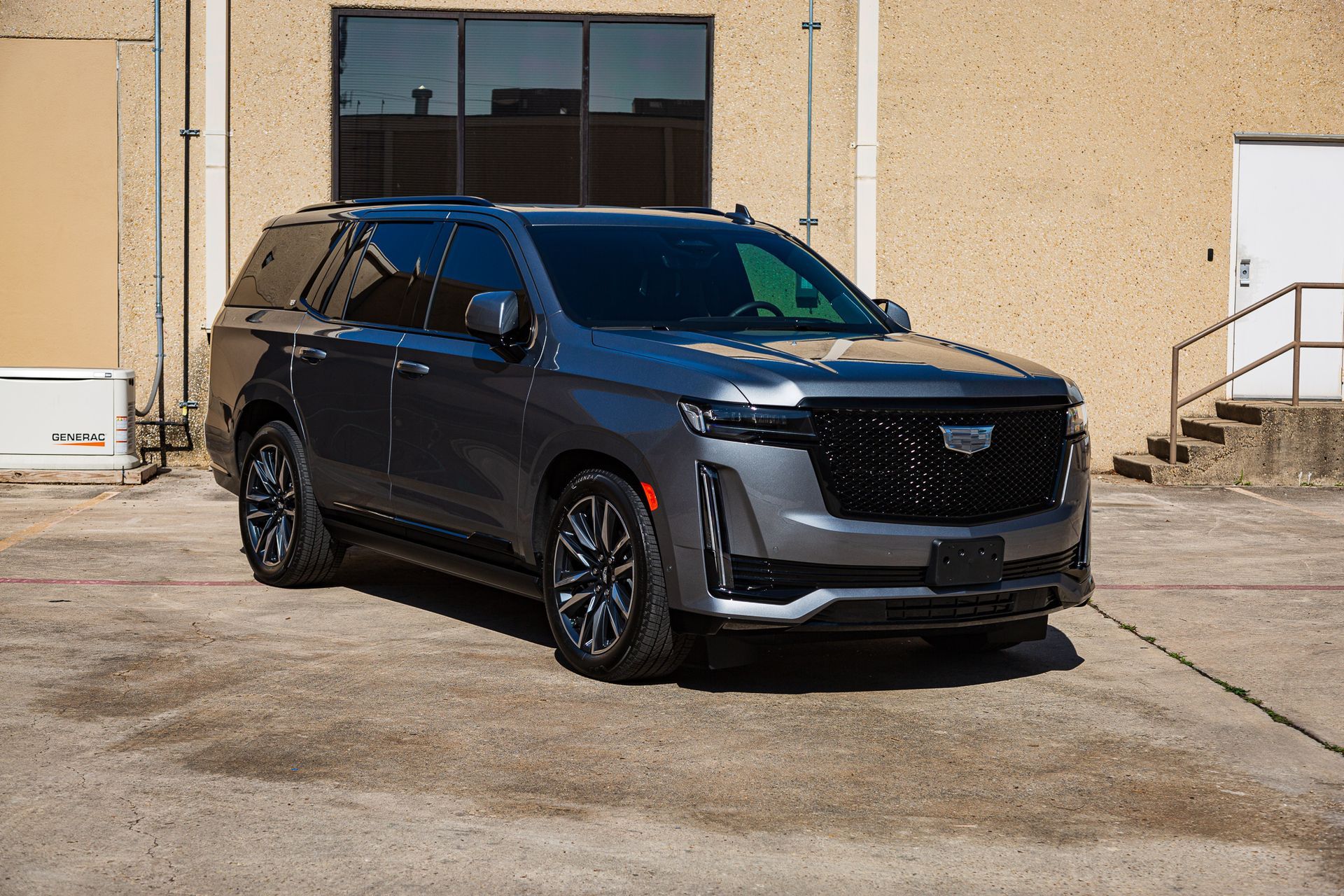 Gray Cadillac Escalade SUV parked outside a tan building.