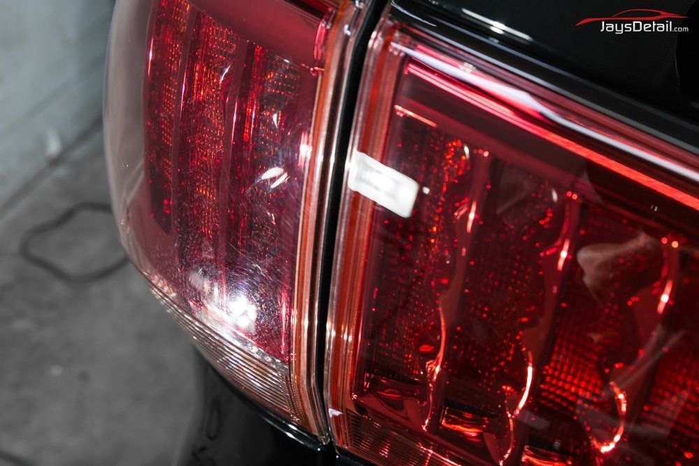 Close-up of a car's red taillight, showing the detailed design and its proximity to the vehicle's edge.
