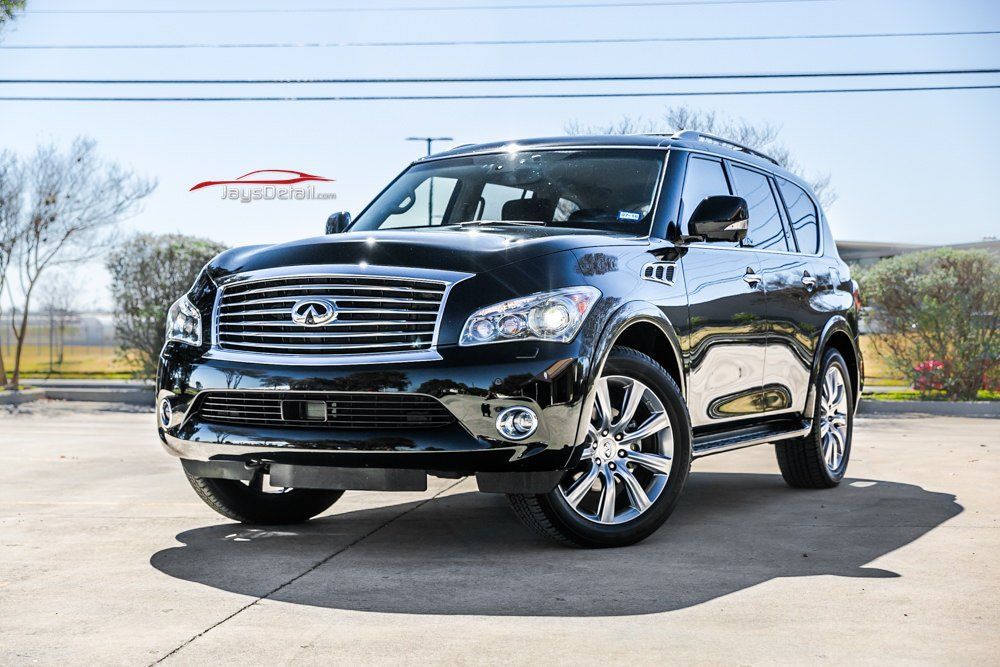 Black Infiniti QX80 SUV parked in a sunny outdoor setting. Shiny chrome accents, chrome wheels.