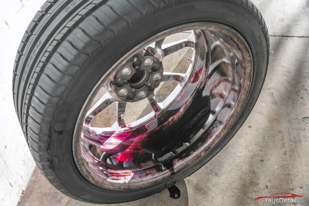 Car tire with chrome rim, leaking dark liquid.