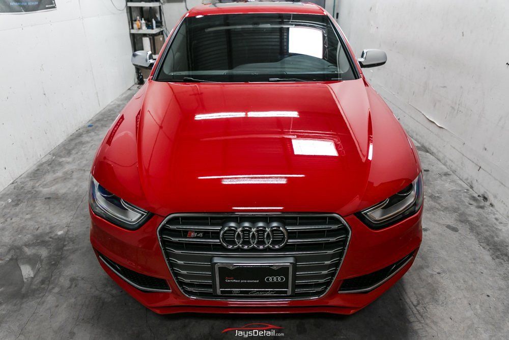 Bright red Audi sedan parked in a garage with a shiny finish.