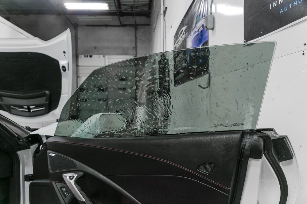 Car window being tinted. The window is covered with film and spray, interior shot.