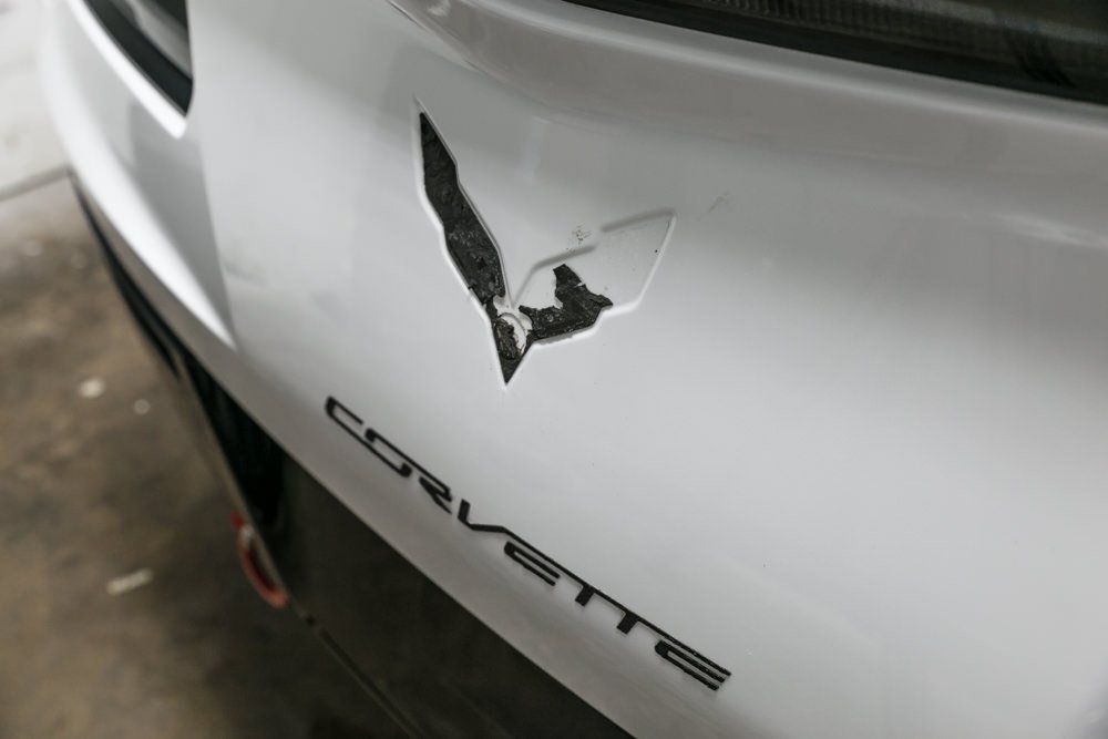 White Corvette hood with damaged emblem and